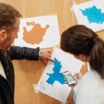 2 Personen schauen auf ausgedruckte Landkarten