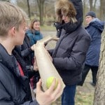 Jugendliche halten mehrere aufgeschnittene Rohrstücke in ihren Händen und balancieren einen Tennisball über diese "Rutsche"